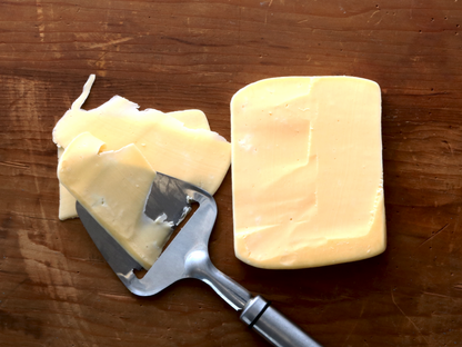 Butterkase cheese on wood surface with cheese planer
